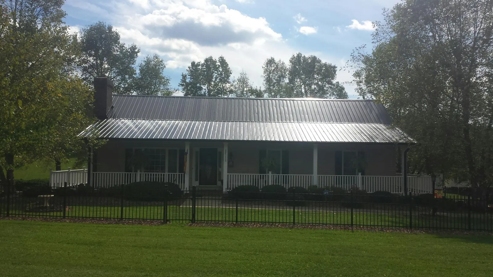 Gray metal roof on a brick ranch with a full width front porch — Gutter Guard Installation work by our crew in Mechanicville