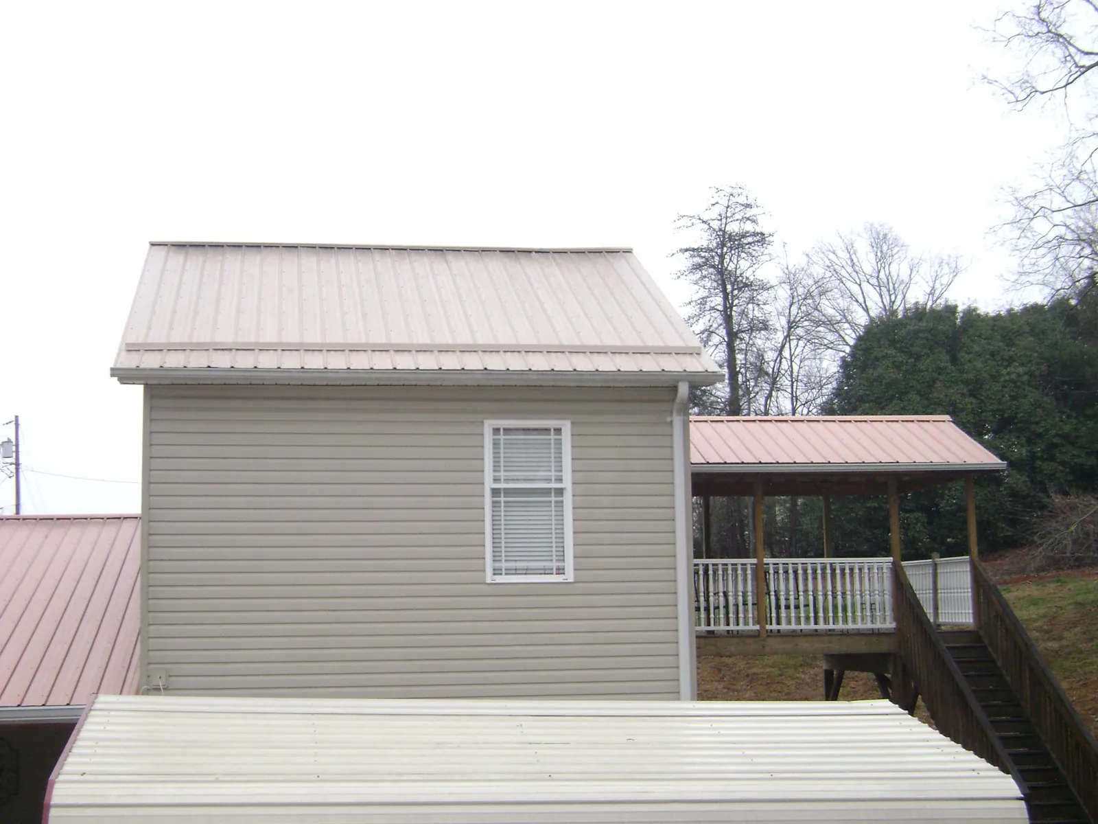 Tan metal roofs on a two story addition and attached porch, from a Roof Replacement job in Mechanicville