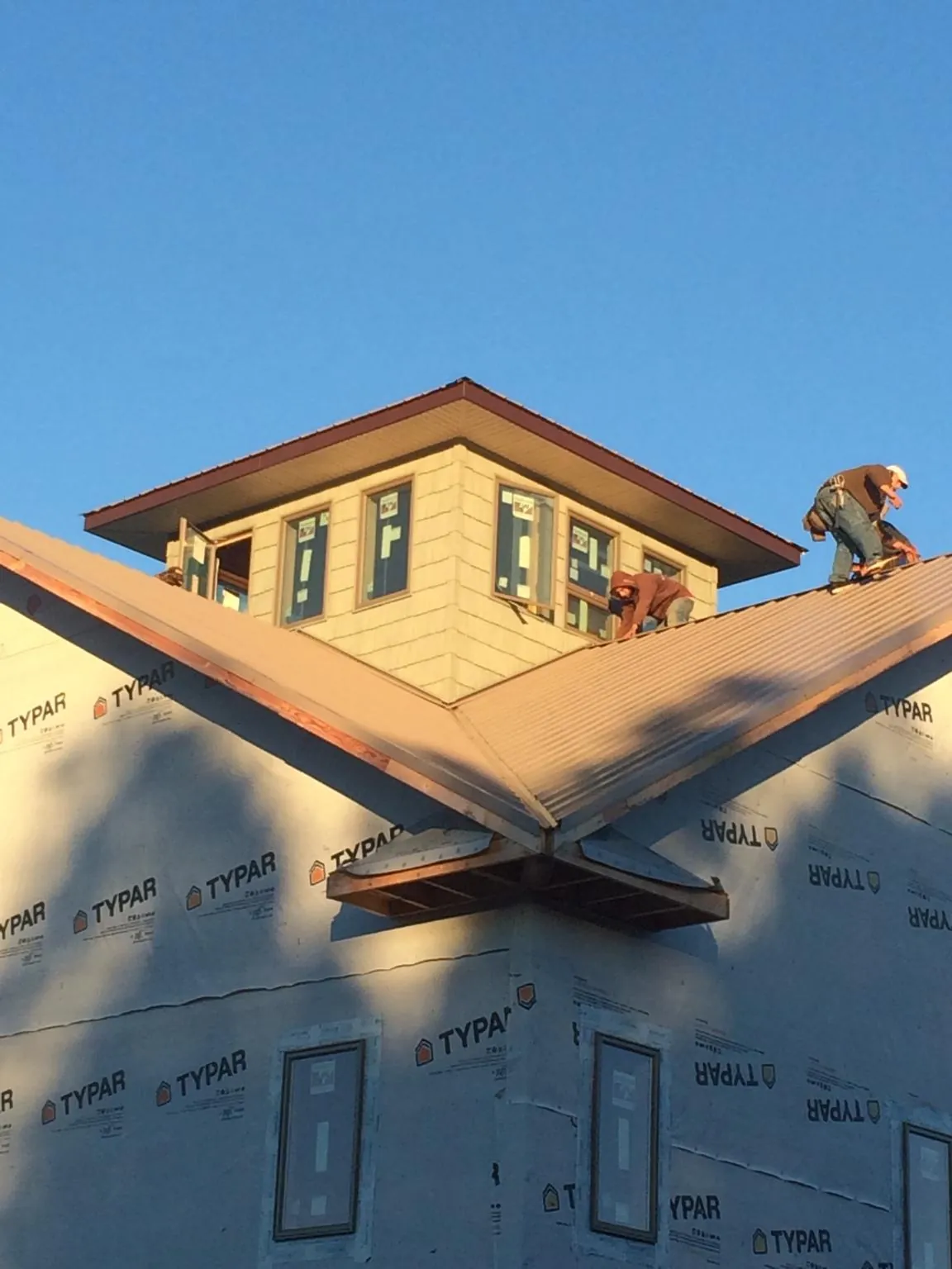 Roofers working around a rooftop cupola on a new metal roof at sunset — Roof Waterproofing in Mechanicville by Roofing Brothers